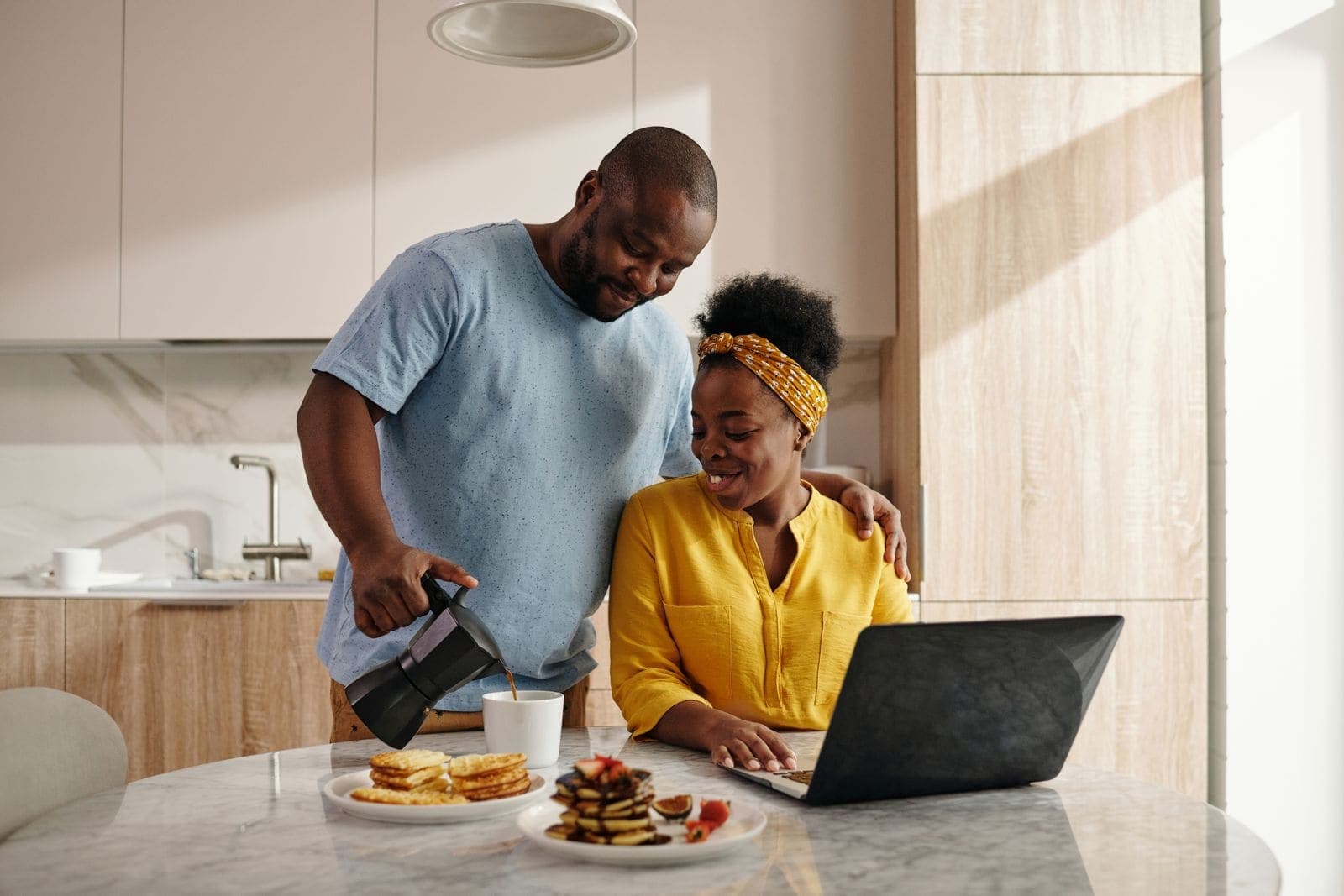 A couple comparing options on a laptop at the kitchen table